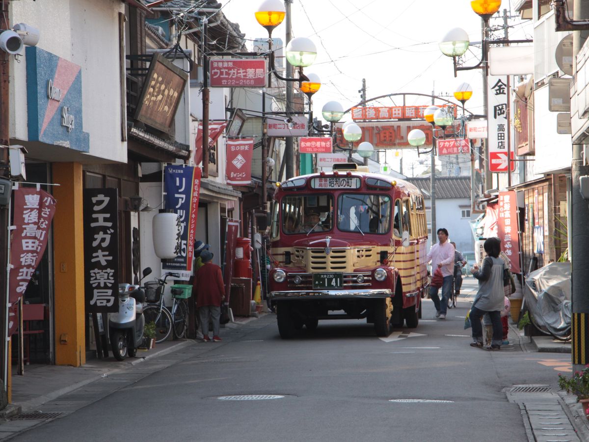 古い型のバスが停まる商店街の通り