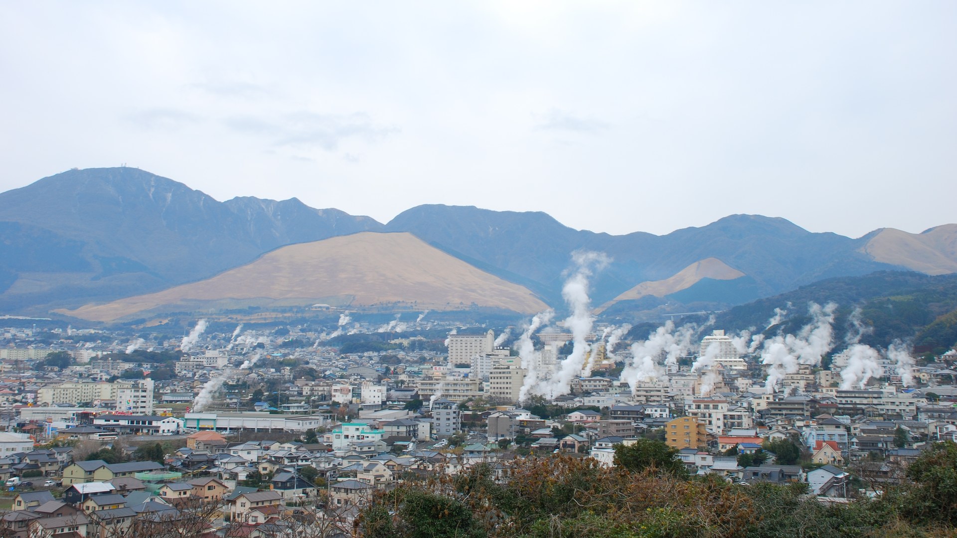 湯けむり展望台から見た別府の街並み。あちこちから湯けむりが上がり、奥に扇山などの山が連なる